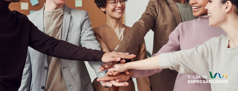 Imagem de uma equipa a dar as mãos, num ambiente de satisfação e descontração. A imagem representação a importância de tratar os colaboradores como clientes de forma a melhor o ambiente da organização.